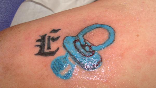 Photo de initiale + tétine bébé, tatouage, bébé réalisé par StudioBeauté